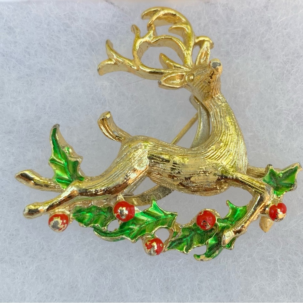 Holiday enamel brooch w/reindeer flying over holly leaves and berries.